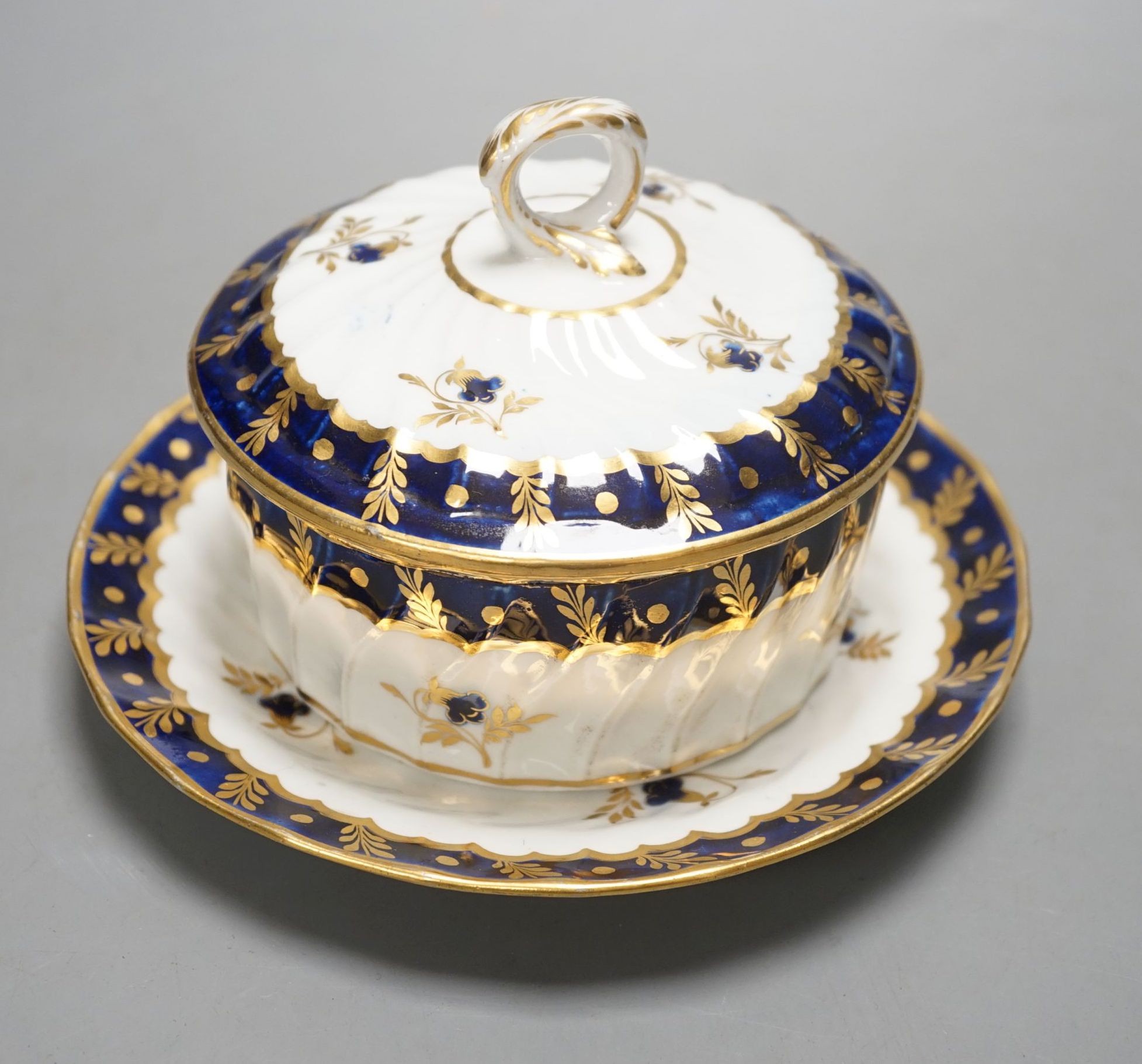 A Chamberlain fine and rare wrythen double tram moulded butter tub, cover and stand decorated in under-glaze blue and gilt c.1800, 12 cms high.